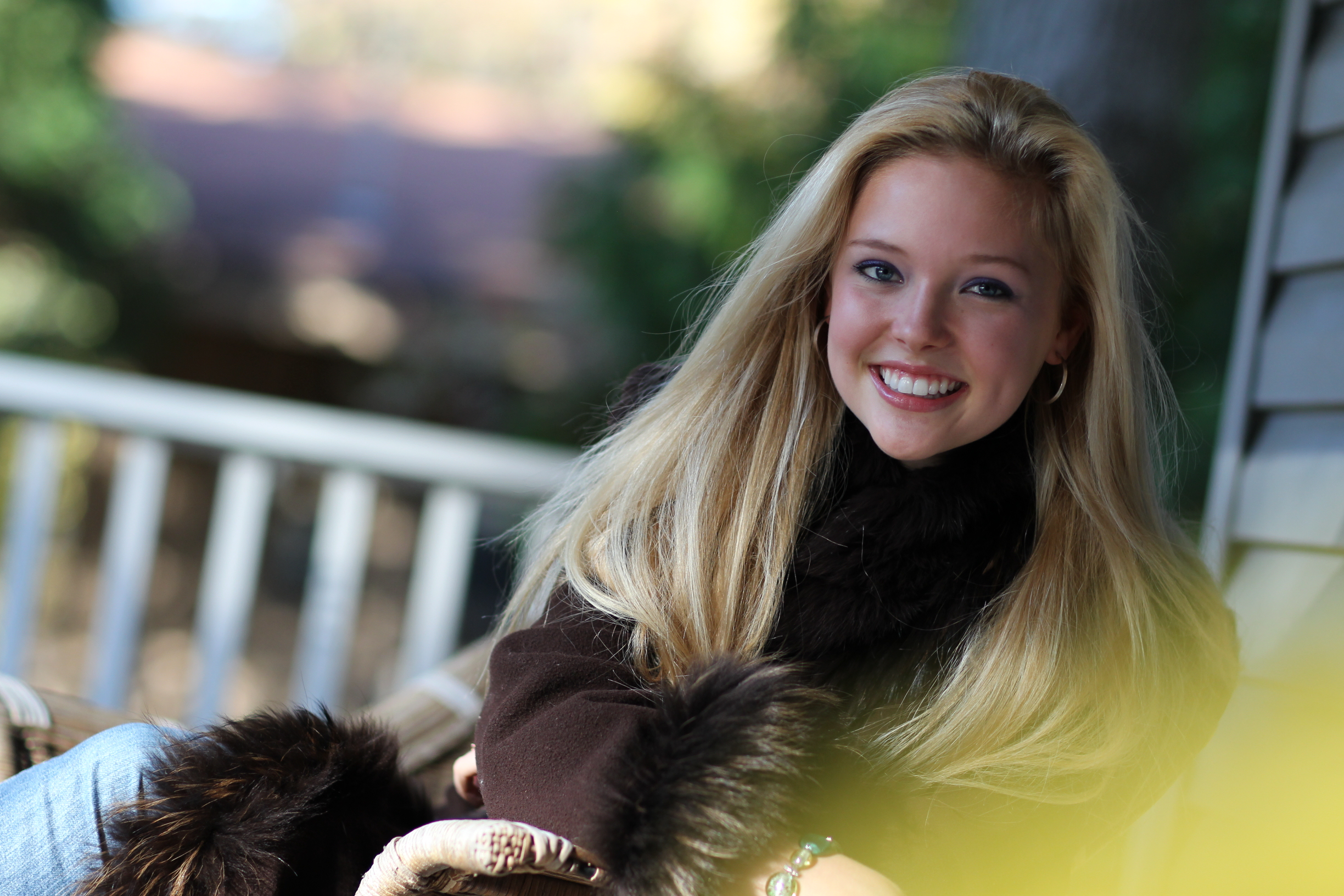 Girl on porch smiling to show the benefits of porcelain veneers